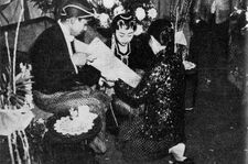 Kacar-kucur ceremony, groom pouring rice and coins into bride's scarf, 1960ح. 1960