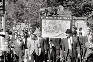 A protest march, with a sign "No More Birminghams" prominent. Some of the marchers are black and some are white; all are well-dressed.
