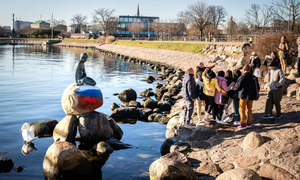 سياح يلتقطون صوراً لتمثال عروس البحر الصغيرة ملطخاً بألوان العلم الروسي