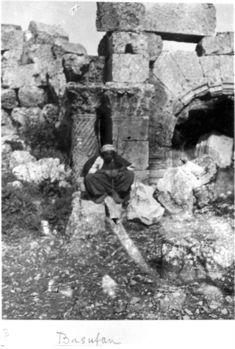 Basufan Church of St. Phocas - Apse and arch of Prothesis - Corinthian columns with spiral fluting and wind blown capital. Kurdish man seated in foreground.jpg