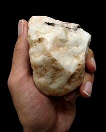 A hand holding a crude stone tool