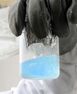 A pale blue liquid in a clear beaker
