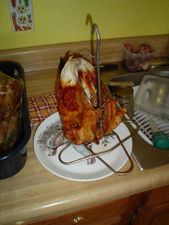 A whole turkey, browned on the outside, on a metal stand.