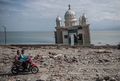 People ride a scooter past a partially submerged mosque in Palu on October 2. The mosque was knocked from its foundation during the quake and tsunami.jpg