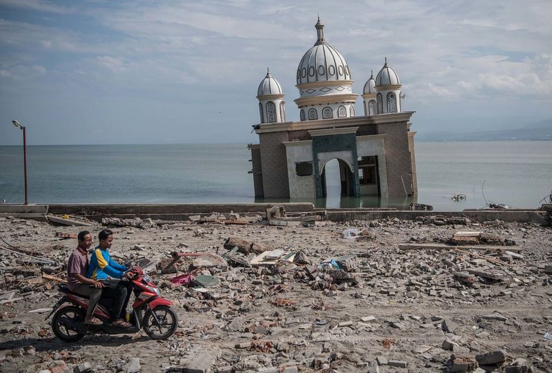 ملف:People ride a scooter past a partially submerged mosque in Palu on October 2. The mosque was knocked from its foundation during the quake and tsunami.jpg