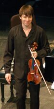 عازف الكمان الأمريكي جوشوا بيل يرتدي الأسود على خشبة المسرح.