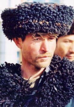 صورة لرجل من الأويغور واقفًا. يرتدي قبعة وله لحية صغيرة.