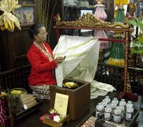 A woman applying "malam" (liquid wax) following pattern on fabric using "canting" in a method of batik-making called "Batik Tulis"