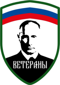 The Logo and patch of the Redut formation "Veterany", with the Russian tricolour at the top horizontally, the edges being green and the below part with white background and a black portrait of Putin in the middle, with the text "Veterany" or "Veterans" written below him.