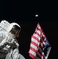 Harrison Schmitt poses with the American flag and Earth in the background during Apollo 17's first EVA. Eugene Cernan is visible reflected in Schmitt's helmet visor
