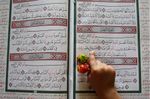 طفل يحمل الحلوى، ويقرأ القرآن خلال شهر رمضان، عمان، الأردن، 22 أغسطس 2009.