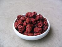 A bowl of reddish-purple, oval-shaped fruits with raisin texture.