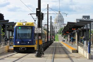A three-car light rail at a station; the state capitol building is in the background.