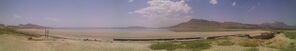 A panoramic view of a desert landscape with a body of water in the distance.