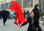 إمرأة تلوح بعلم تونس وسط انتشار ضباط الشرطة التونسية، يناير 2011.