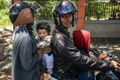 A family on a motorcycle waits to learn the status of relatives on October 2.jpg