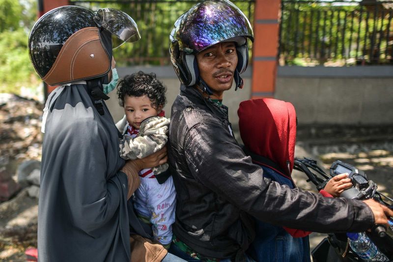 ملف:A family on a motorcycle waits to learn the status of relatives on October 2.jpg