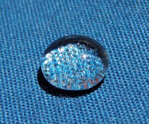 A shiny spherical drop of water on blue cloth