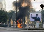أدخنة اللهب تتصاعد في أحد شوارع تونس العاصمة، وصورة للرئيس السابق بن علي.