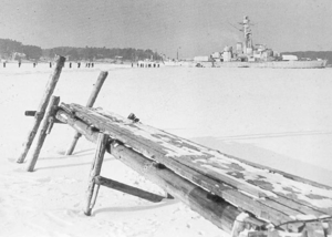 Frozen sea with a dock in front and a ship in behind.