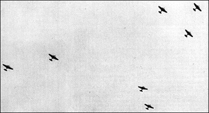 A distant photo taken from ground where several bombers are flying in the air.