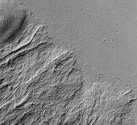 Mars Global Surveyor image showing lava flows of different ages at the base of Olympus Mons. The flat plain is the younger flow. The older flow has lava channels with levees along the edges. Levees are quite common to lava flows on Mars.